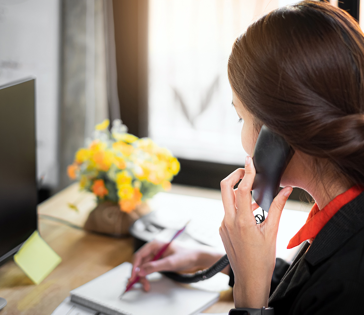 Business woman note schedule on book and talking with customer by telephone.